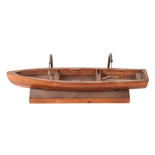 412 - A teak scale model of a rowing boat, 30cm long, mounted on a brass and wooden stand.