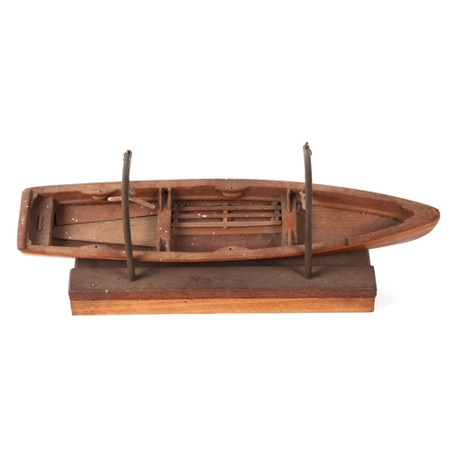 412 - A teak scale model of a rowing boat, 30cm long, mounted on a brass and wooden stand.