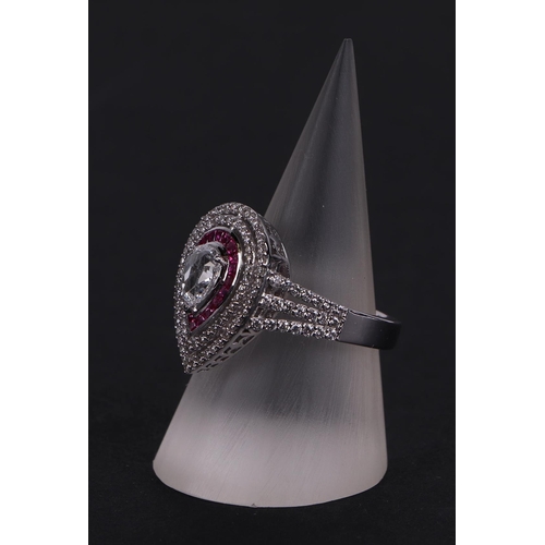 519 - An 18ct white gold ring set with a large pear-shaped rose cut diamond, within a calibre rubies and a... 