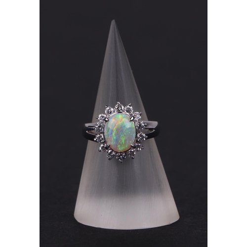 521 - A platinum ring, set with an oval opal cabochon, within a halo of diamonds, opal approx 1.05ct, appr... 