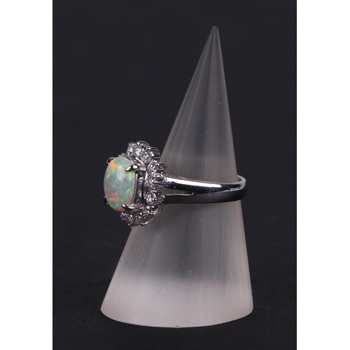 521 - A platinum ring, set with an oval opal cabochon, within a halo of diamonds, opal approx 1.05ct, appr... 