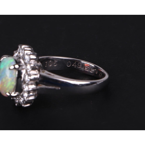 521 - A platinum ring, set with an oval opal cabochon, within a halo of diamonds, opal approx 1.05ct, appr... 