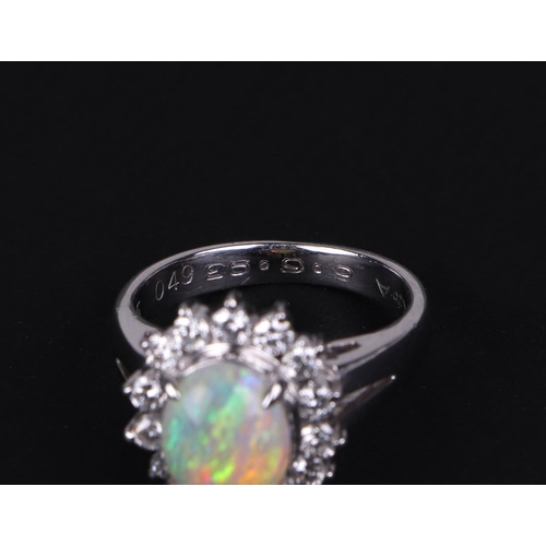 521 - A platinum ring, set with an oval opal cabochon, within a halo of diamonds, opal approx 1.05ct, appr... 