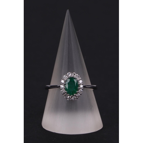 527 - An 18ct white gold oval emerald and diamond cluster ring, approx UK size N.