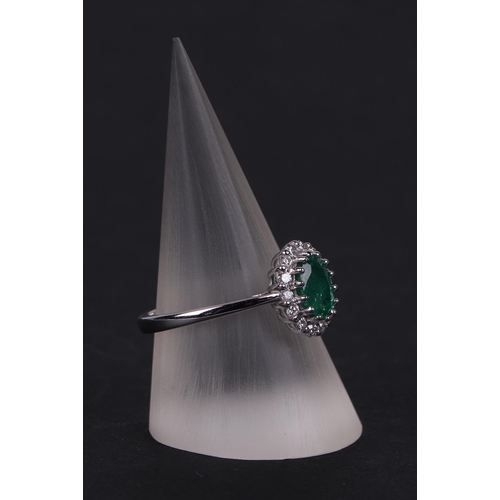 527 - An 18ct white gold oval emerald and diamond cluster ring, approx UK size N.