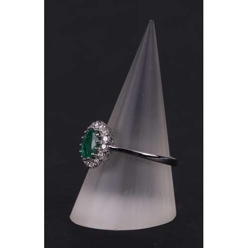 527 - An 18ct white gold oval emerald and diamond cluster ring, approx UK size N.