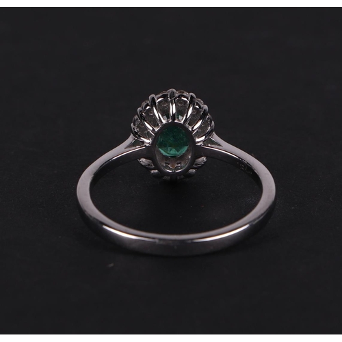 527 - An 18ct white gold oval emerald and diamond cluster ring, approx UK size N.