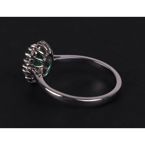 527 - An 18ct white gold oval emerald and diamond cluster ring, approx UK size N.