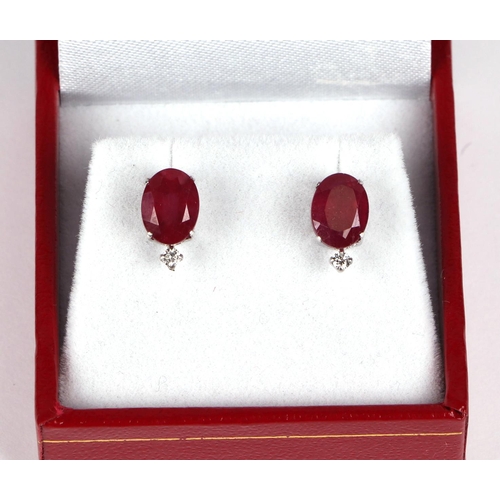 534 - A pair of platinum stud earrings set with oval cut treated rubies and a single diamond, rubies appro... 