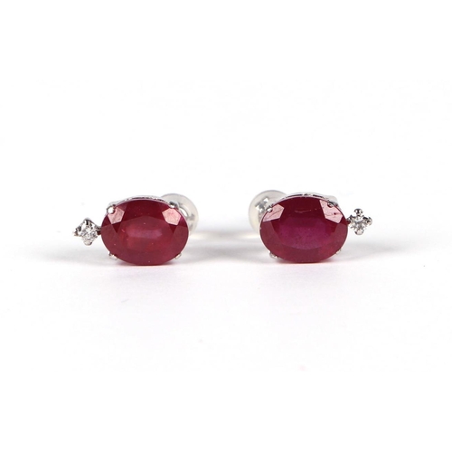 534 - A pair of platinum stud earrings set with oval cut treated rubies and a single diamond, rubies appro... 