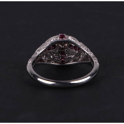 538 - An art deco style platinum ring, set with a central diamond calibre cut rubies and further diamonds,... 