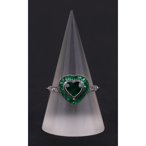 539 - A platinum ring set with a heart shaped emerald, surround by calibre cut emeralds and diamond set sh... 