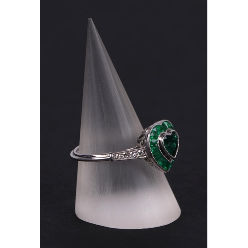 539 - A platinum ring set with a heart shaped emerald, surround by calibre cut emeralds and diamond set sh... 