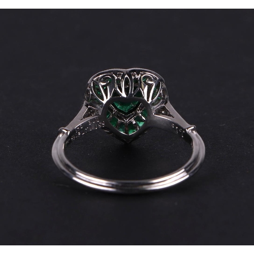 539 - A platinum ring set with a heart shaped emerald, surround by calibre cut emeralds and diamond set sh... 