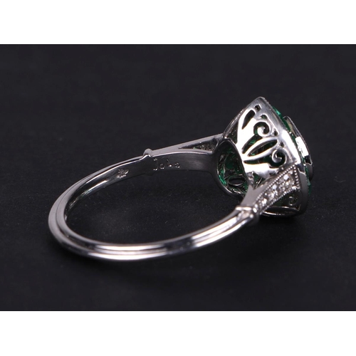 539 - A platinum ring set with a heart shaped emerald, surround by calibre cut emeralds and diamond set sh... 