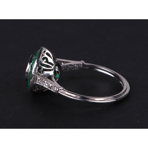 539 - A platinum ring set with a heart shaped emerald, surround by calibre cut emeralds and diamond set sh... 