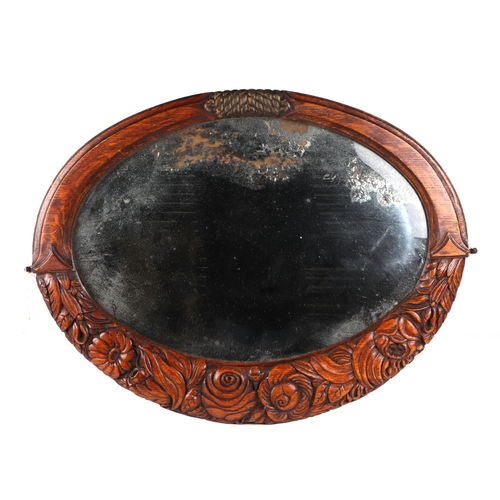 827 - An Arts and Crafts style carved oak oval wall mirror with oval bevelled plate, 71cm wide.