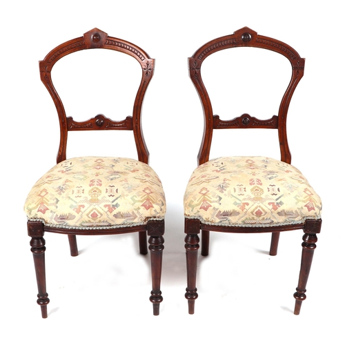 831 - A set of four Victorian walnut balloon back chairs with upholstered seat on turned front supports. (... 