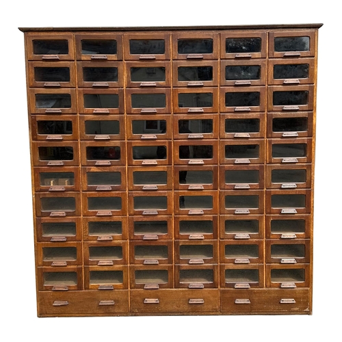 832 - A mid century substantial haberdashery cabinet, with sixty oak fronted glazed drawers, above three l... 