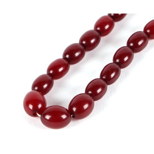 541 - A graduated string of cherry amber like  Bakelite beads, approx 50cm long, largest bead 10mm long, 1... 