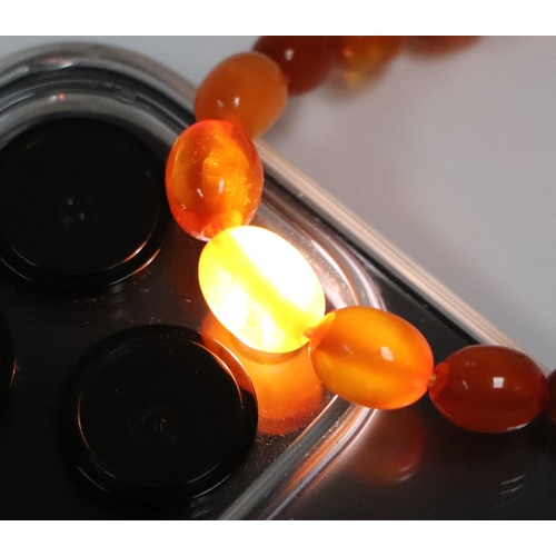 541 - A graduated string of cherry amber like  Bakelite beads, approx 50cm long, largest bead 10mm long, 1... 