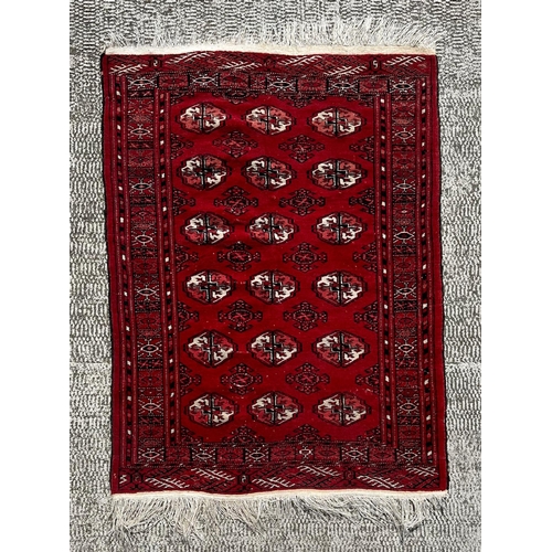 137 - A Caucasian rug with repeating guls on a red ground, within a multi geometric boarder, 102 by 136cm.