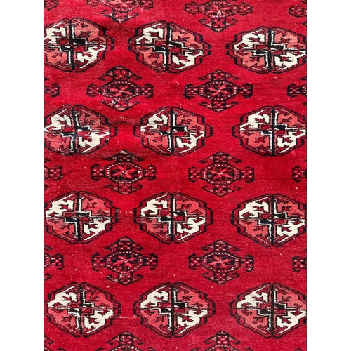 137 - A Caucasian rug with repeating guls on a red ground, within a multi geometric boarder, 102 by 136cm.