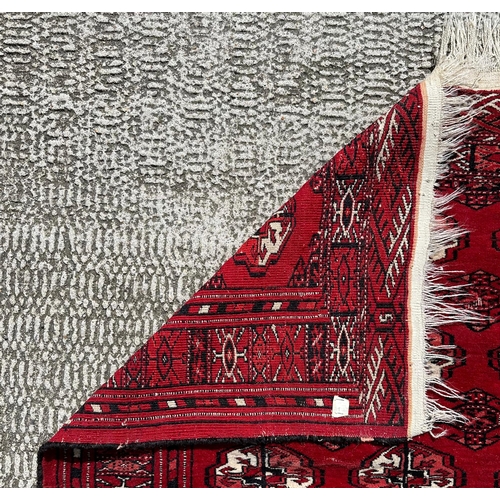 137 - A Caucasian rug with repeating guls on a red ground, within a multi geometric boarder, 102 by 136cm.
