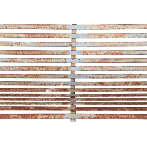 26 - A well weathered painted iron strap work garden bench, with scroll arms and feet, and ball finials, ... 