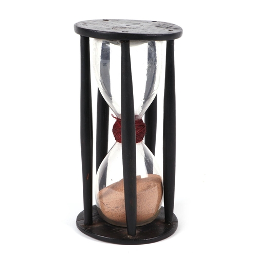 387 - An early 18th / late 19th century hourglass within a treen cage, 18cm high.