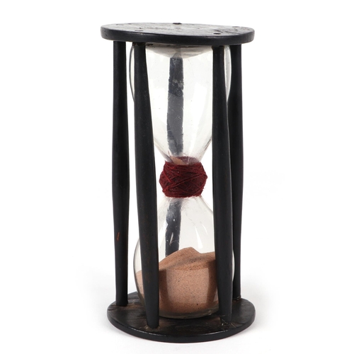 387 - An early 18th / late 19th century hourglass within a treen cage, 18cm high.