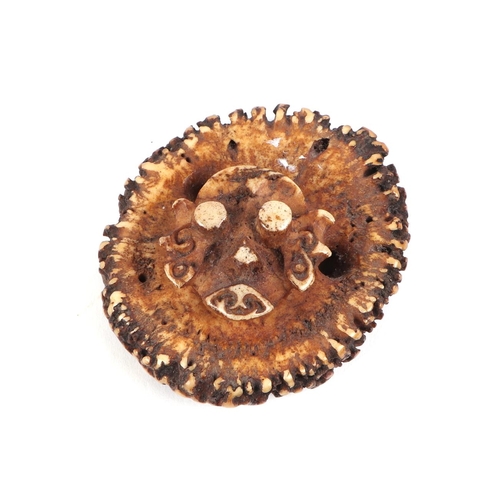 424 - A stags horn toggle, each side carved with a stylised face, approx 6cm diameter.