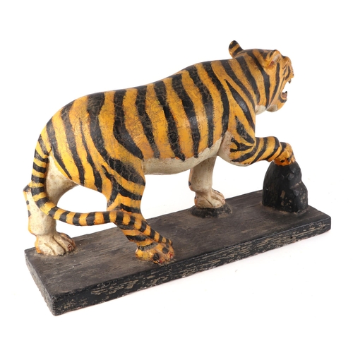 439 - A large Burmese painted hardwood figure of a tiger mounted on a plinth, 60cm wide.