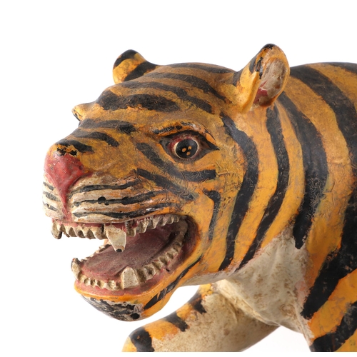 439 - A large Burmese painted hardwood figure of a tiger mounted on a plinth, 60cm wide.