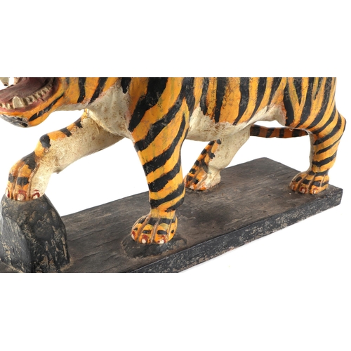 439 - A large Burmese painted hardwood figure of a tiger mounted on a plinth, 60cm wide.