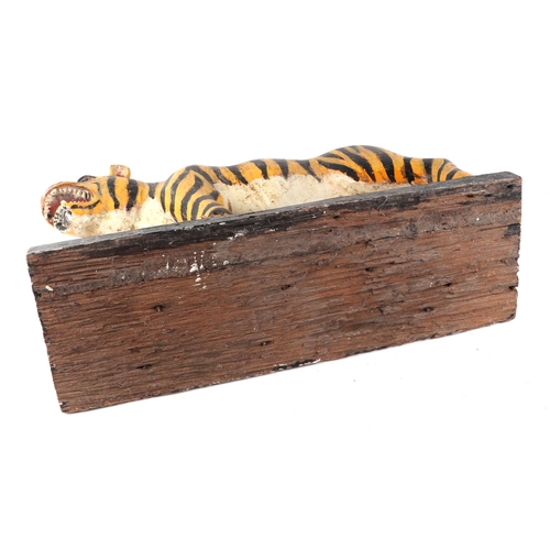 439 - A large Burmese painted hardwood figure of a tiger mounted on a plinth, 60cm wide.