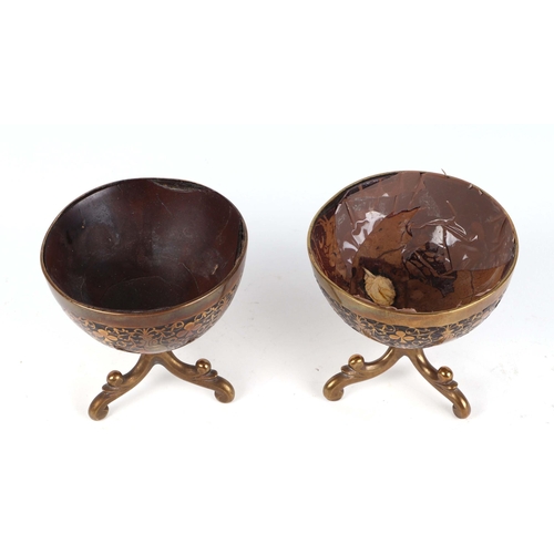 275 - A pair of 19th century brass inlaid coconut bowls on tripod stands decorated with monkeys, 9cms high... 