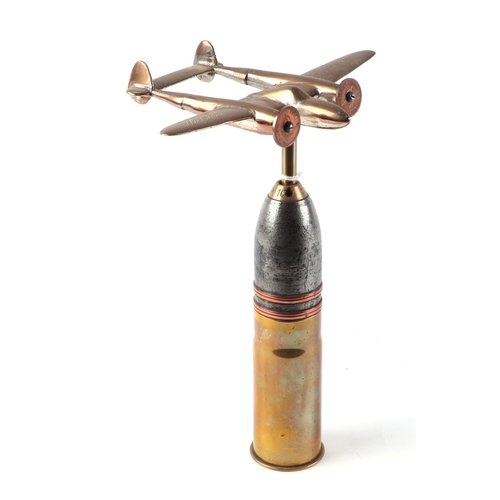 28 - A trench art cast brass model of a Lockheed P-38 Lightning, mounted on a shell case, wingspan 16cm.