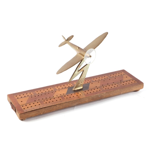 36 - A trench art cast brass model of a Spitfire aircraft, mounted on a cribbage board, wingspan 13cm.