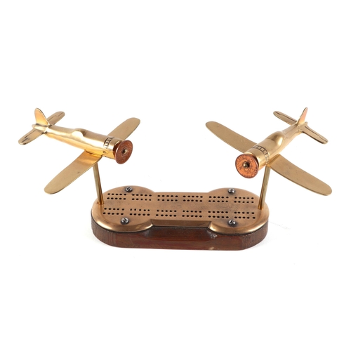 45 - A pair of trench art cast brass model of Wildcat aircrafts, mounted on a cribbage board, 34cm wide.