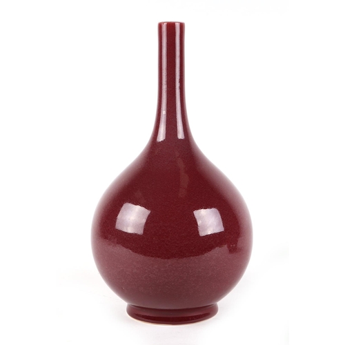 539 - A Chinese ox blood glazed bottle vase on hardwood stand, 34cms high.