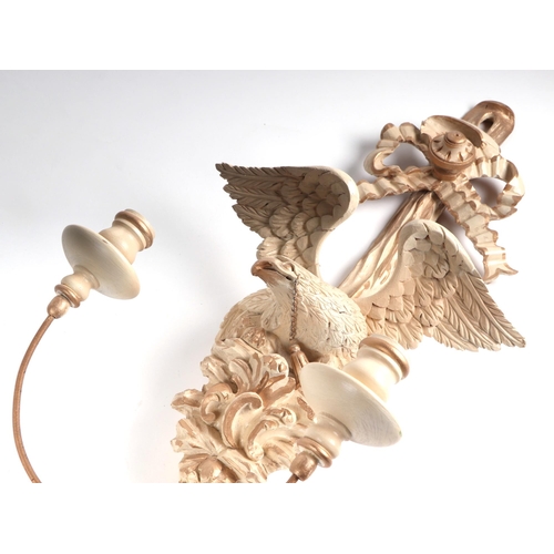 593 - A continental carved wood and painted gesso twin-branch wall light with ribbon tie and eagle surmoun... 