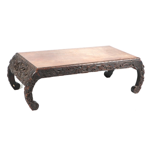 740 - An Oriental kang or low table, the frieze and scroll legs with profusely carved decoration, 104cm wi... 