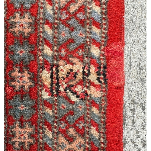 81 - A large Persian Turkoman runner with repeating guls and geometric motifs, on a red ground within a m... 