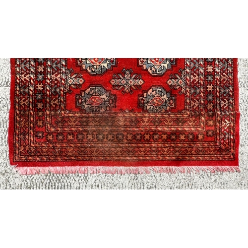 81 - A large Persian Turkoman runner with repeating guls and geometric motifs, on a red ground within a m... 