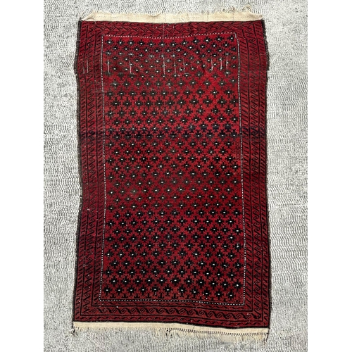 85 - A Persian Turkoman hand knotted rug with repeated design, on a red ground, 170 by 102cms.