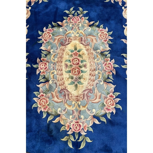 91 - A Chinese woollen floral design rug on a blue ground, 277 by 182cms.