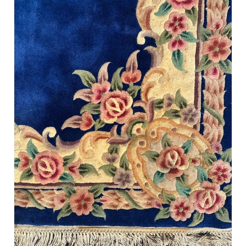 91 - A Chinese woollen floral design rug on a blue ground, 277 by 182cms.