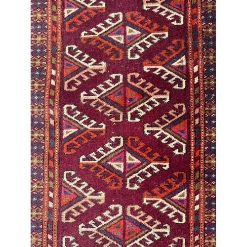 94 - A Persian Balouch hand knotted woollen rug with all over geometric design, on a red ground, 108 by 5... 