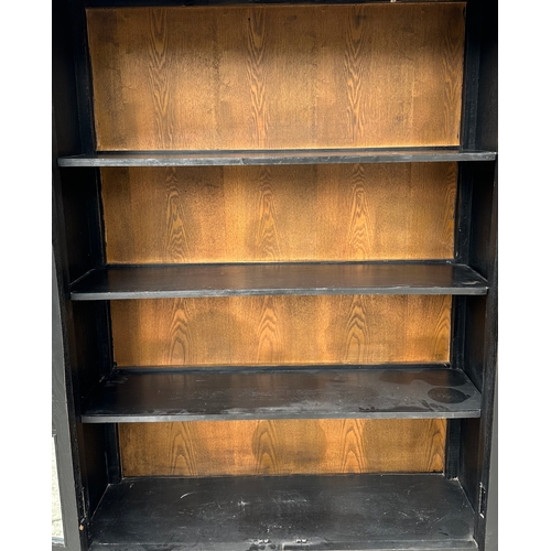 727 - A Chinese ebonised elm bookcase on cupboard in the European taste with a moulded cornice above a pai... 